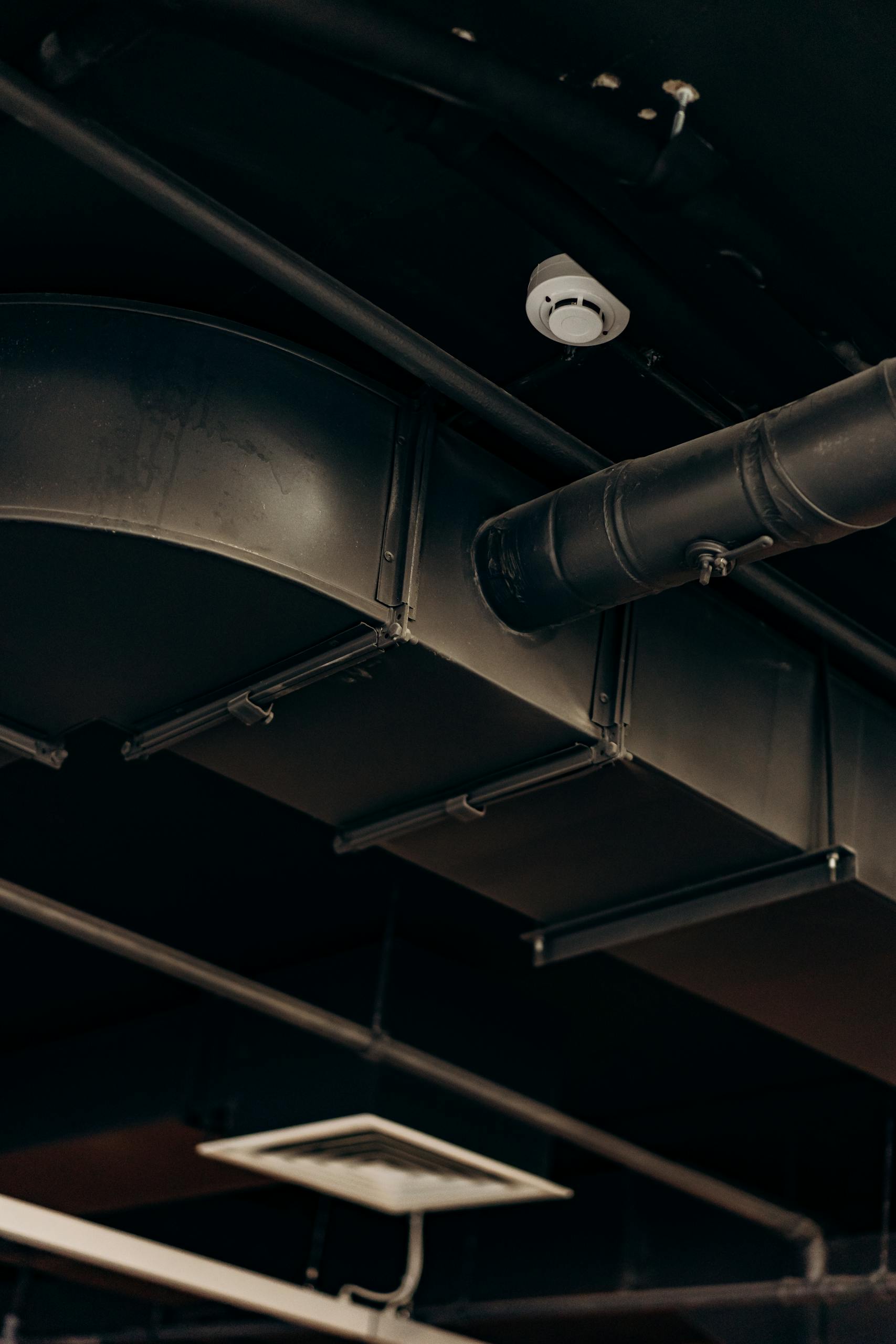 Detailed view of industrial air ducts on a ceiling, showcasing modern urban design.